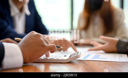 close-up and cropped image, A businessman using a calculator during the financial meeting with her team. Stock Photo