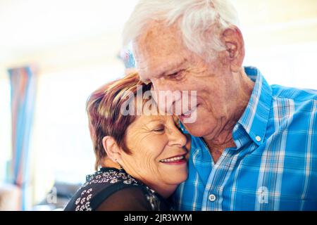 Literally together forever. a cheerful elderly couple holding each other and laughing while standing inside of a building. Stock Photo