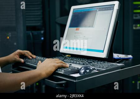 Your computer network in expert hands. an IT technician using a computer while working in a data center. Stock Photo