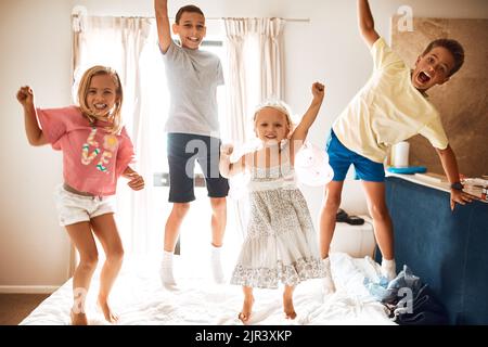 Theyve got endless energy. Portrait of little siblings jumping on a bed at home. Stock Photo
