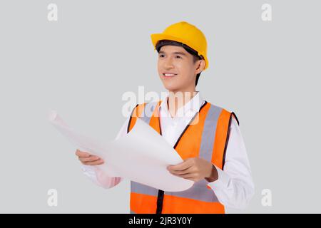 Portrait young asian man is engineer wearing helmet holding and looking blueprint with confident isolated on white background, handsome male is archit Stock Photo