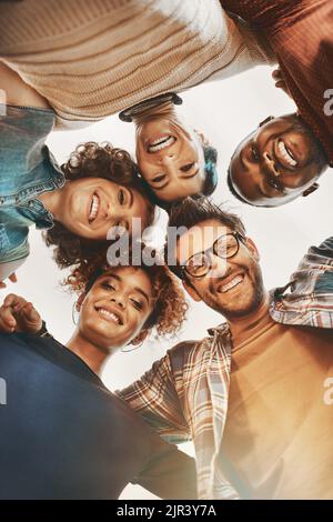 Stay positive. Work hard. Make it happen. Low angle shot of creative employees huddled together at work. Stock Photo