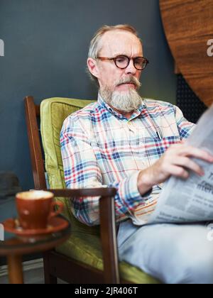 Coffee and newspaper, how I love to start my afternoons. a senior man reading the newspaper and having coffee at a coffee shop. Stock Photo
