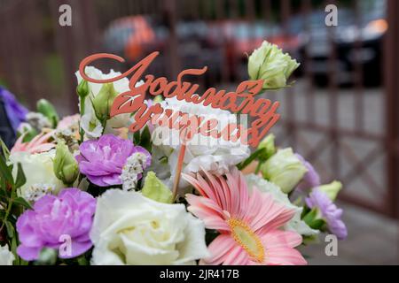 white gift card with the inscription happy teacher's day in a bouquet of bright beautiful multi-colored roses, the concept of congratulations on the h Stock Photo