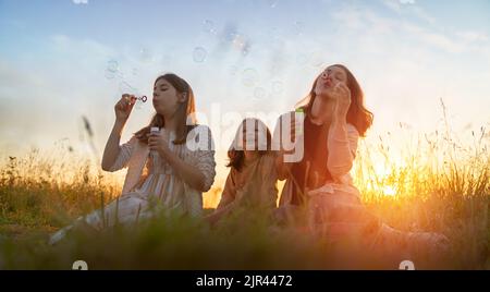 Happy family at sunset. Mother and children are running, having fun and enjoying summer evening. Stock Photo