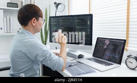 Software development concept, Male programmer checking website programming and drinking coffee. Stock Photo