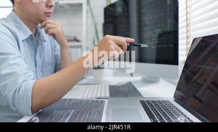 Software development concept, Male programmer pointing on laptop screen to checking data codes. Stock Photo