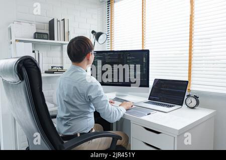 Software development concept, Male programmer typing data code and working on multiple screens. Stock Photo