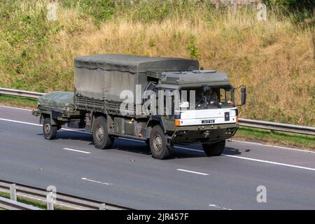 British Army green dropside General Service truck, canvas-covered MAN HX60 18.330 4x4 Military vehicle towing a trailer; travelling on the M6 Motorway UK Stock Photo