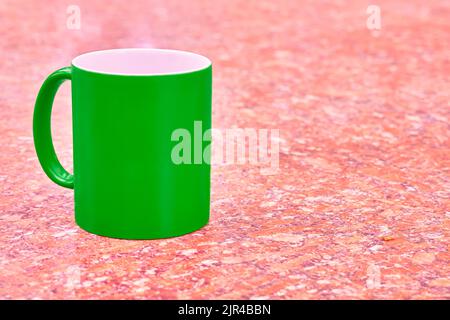 Green ceramic cup mug on bright red white spotted background Stock Photo
