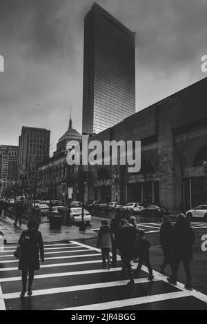 A grayscale shot of pedestrians crossing the street in front of the Boston Public Library in Boston, Massachusetts Stock Photo