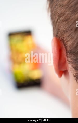 A young man using a mobile phone while surfing social networks. User browsing media content on smartphone on white close up Stock Photo