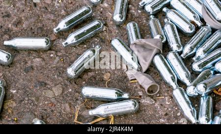 Discarded Nitrous Oxide canisters and grey balloon Stock Photo