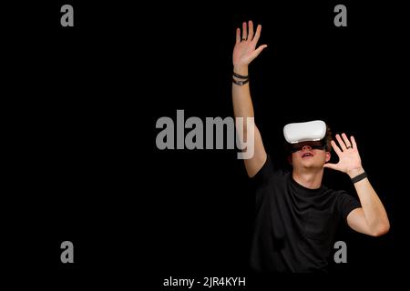 Young man wearing virtual reality VR glasses, goggles isolated on black background. Inside A Metaverse Stock Photo