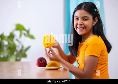 Portrait of cheerful girl holding a segmented slice of mango Stock Photo