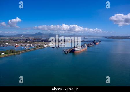 Aerial view of a busy industrial cargo port with ships and cranes against a clear sky Stock Photo