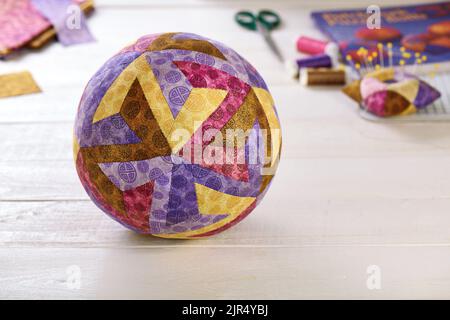 Patchwork ball made of pieces of fabric sewn in the shape of the letter Z on the background of quilting and sewing accessories Stock Photo
