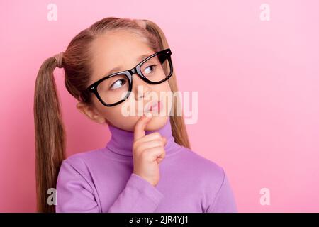 Photo of pretty interested wondering little girl in spectacles look empty space brainstorming isolated on pink color background Stock Photo