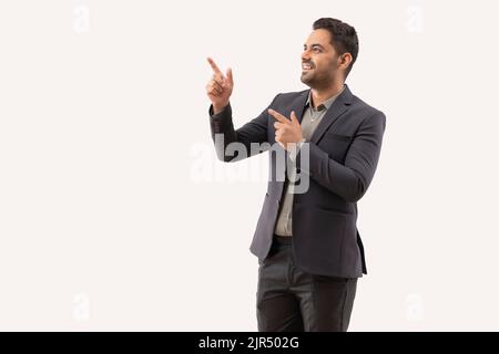 Cheerful young businessman pointing against white background Stock Photo