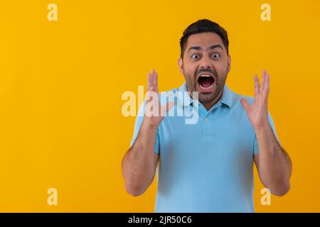 Portrait of an angry young man shouting against yellow background Stock Photo