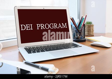 Laptop with text DE and I (diversity, equity, inclusion) program on screen at workplace Stock Photo