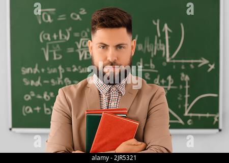 Handsome Math teacher with books in classroom Stock Photo