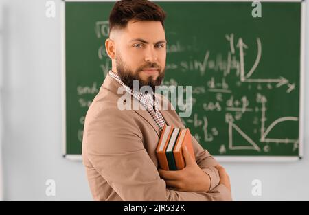 Handsome Math teacher with books in classroom Stock Photo