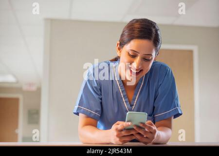 Portrait of smiling female nurse using Smartphone in hospital Stock Photo