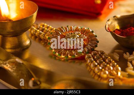 Close up of a beautiful rakhi kept in a plate with diya and rice Stock Photo