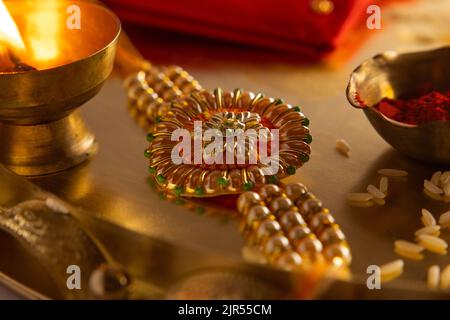 Close up of a beautiful rakhi kept in a plate with diya and rice Stock Photo