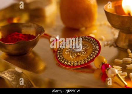 Close up of a beautiful rakhi kept in a plate with diya and rice Stock Photo