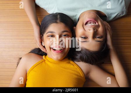 Close-up of boy and girl lying down on wooden floor Stock Photo