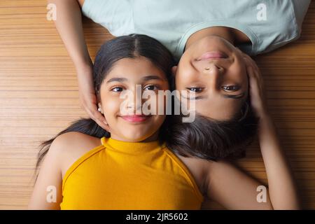 Close-up of boy and girl lying down on wooden floor Stock Photo