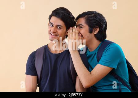 Portrait of two teenage boys whispering to each other Stock Photo