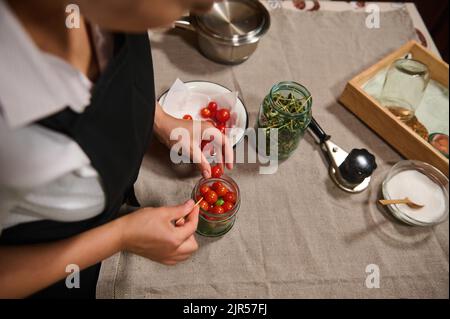 Top view of a housewife pickling tomatoes. Canning. Marinating. Preparing fermented salted vegetables for winter Stock Photo