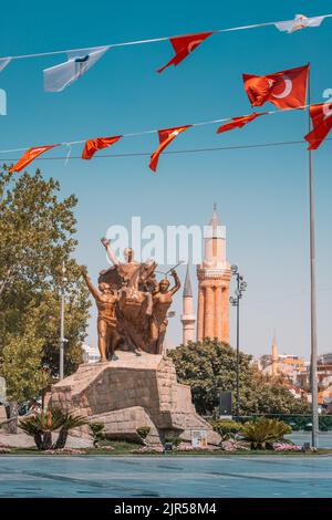 07 July 2022, Antalya, Turkey: Mustafa Kemal Ataturk equestrian statue on a square in Antalya decorated with Turkish flags. Yivli minaret and Old town Stock Photo