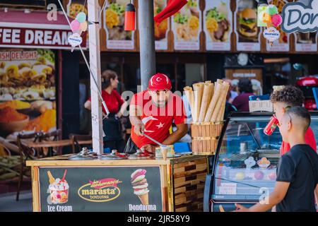 07 July 2022, Antalya, Turkey: The seller of traditional Turkish ice cream making funny show and tricks before selling sweets to the tourists Stock Photo