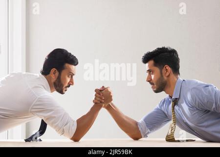 Corporate employees in formal clothing engaged in an arm wrestling match. Stock Photo