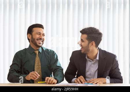 Corporate co-workers talking and laughing while sitting together. Stock Photo