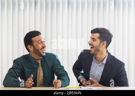 Corporate co-workers talking and laughing while sitting together. Stock Photo