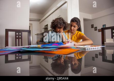 Mother helping her son during painting in living room Stock Photo