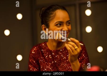 Young woman laughing while applying make-up Stock Photo