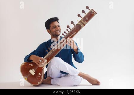 Portrait of cheerful young man playing sitar Stock Photo