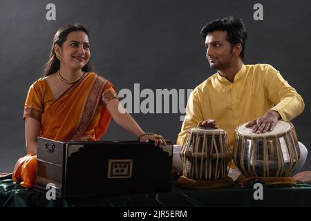 Man and woman performing together with harmonium and Tabla in a classical musical concert Stock Photo