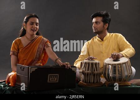 Man and woman performing together with harmonium and Tabla in a classical musical concert Stock Photo