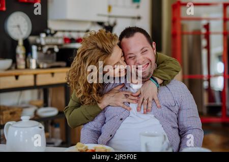 Portrait of mother hugging her grown up son with Down syndrome, motherhood concept. Looking at camera. Stock Photo