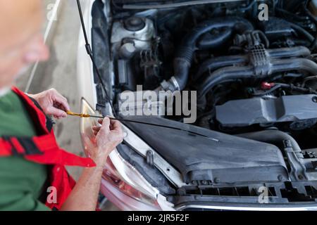 Senior mechanic checking the oil level in the car engine. Stock Photo