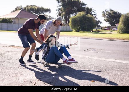 Image of happy diverse female and male friends having fun on skateboard Stock Photo