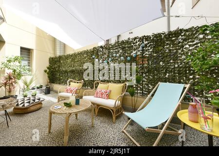 Terrace with fabric and wood hammocks, wicker furniture with fabric seats, decorative plants and stone floors Stock Photo