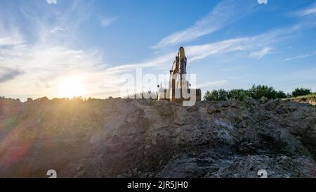 Sunrise or sunset behind a large construction excavator of yellow color on the construction site in a quarry for quarrying. Industrial image. High quality photo Stock Photo